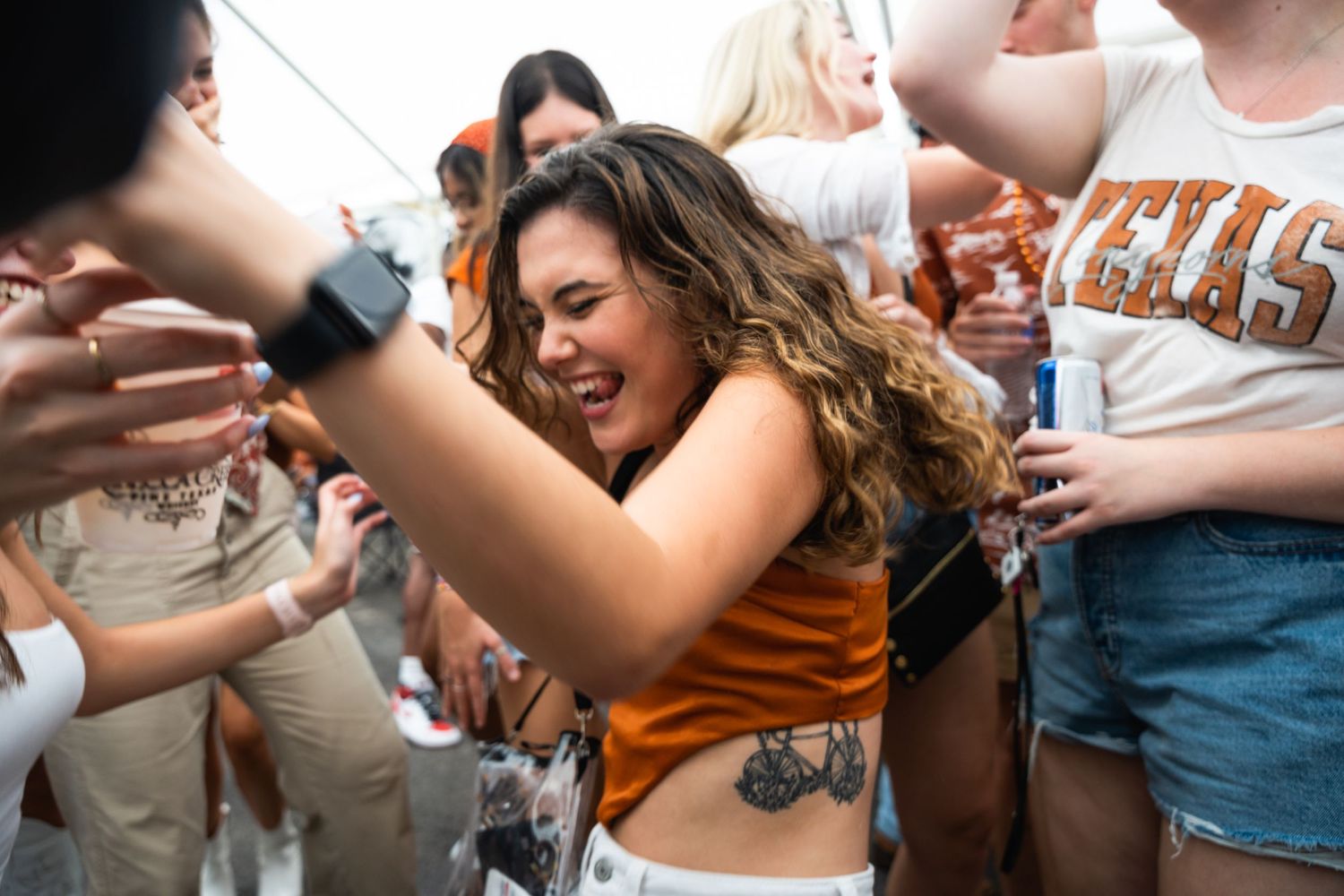 Partygoers in Texas-themed attire dancing and celebrating at an outdoor gathering.