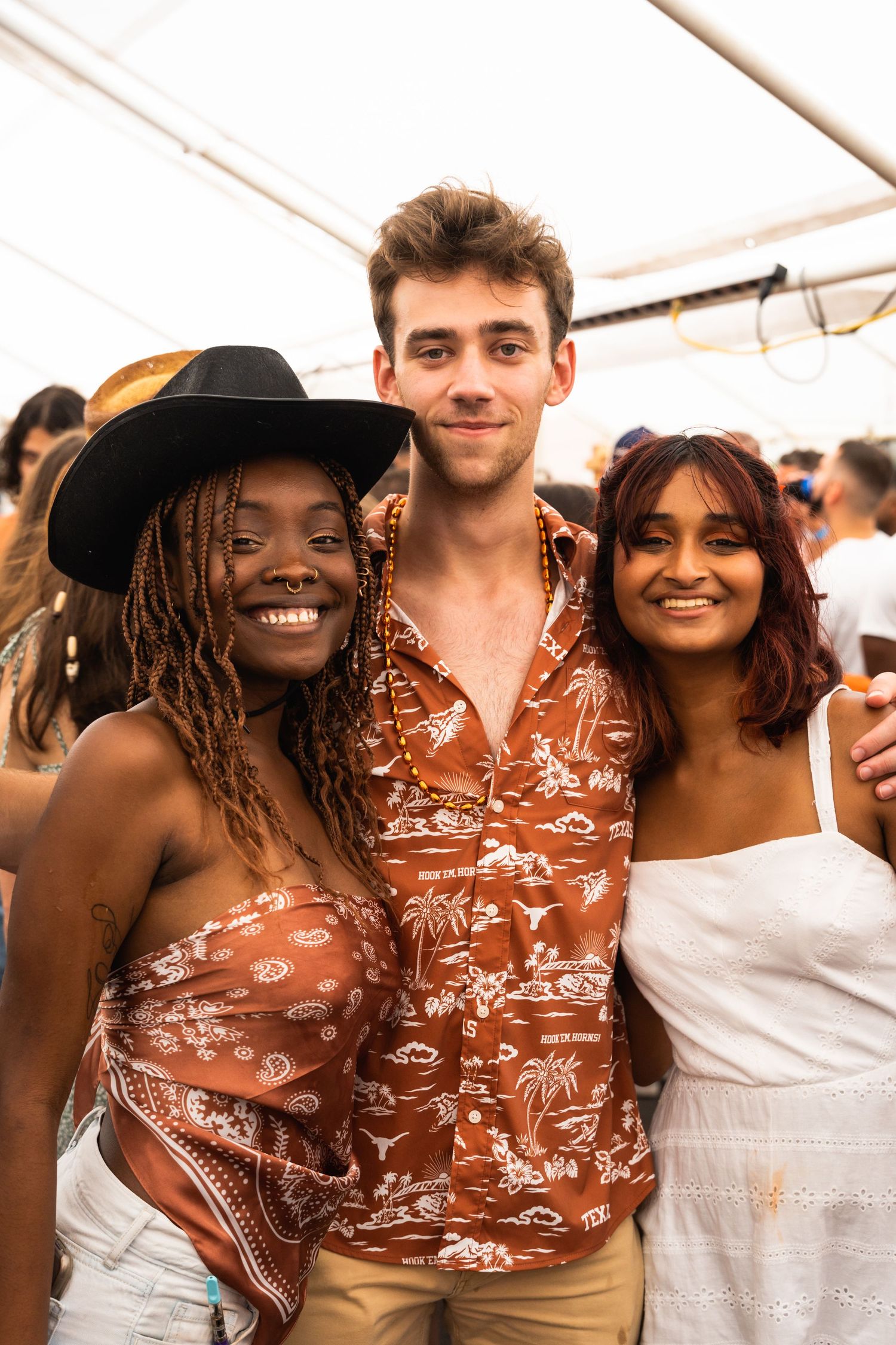 Three friends enjoying a summer festival together wearing coordinated brown and white outfits.