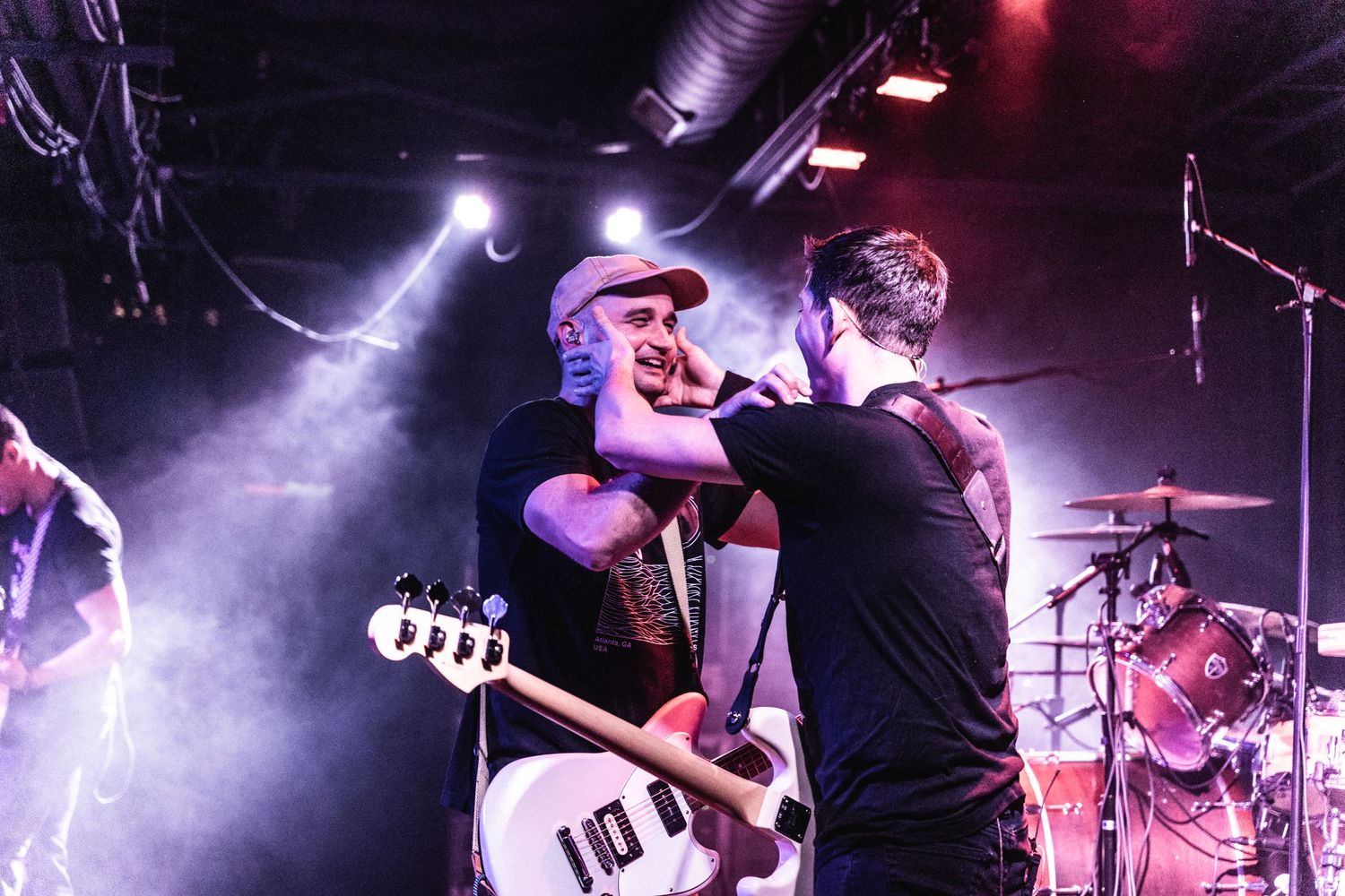 Musicians performing passionately on stage with dramatic purple smoke and lighting effects.