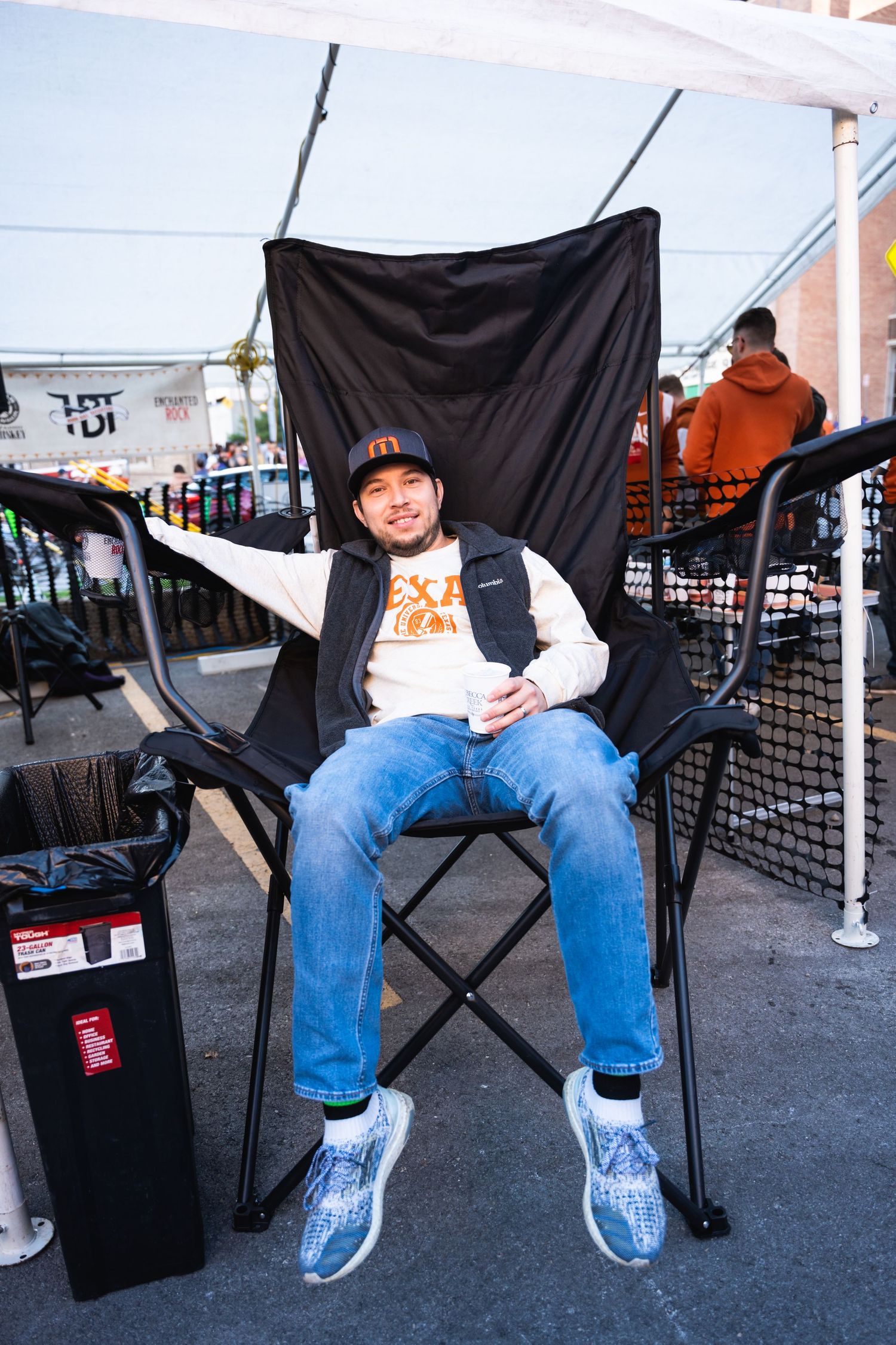 A person relaxes in a camping chair at an outdoor event setup.