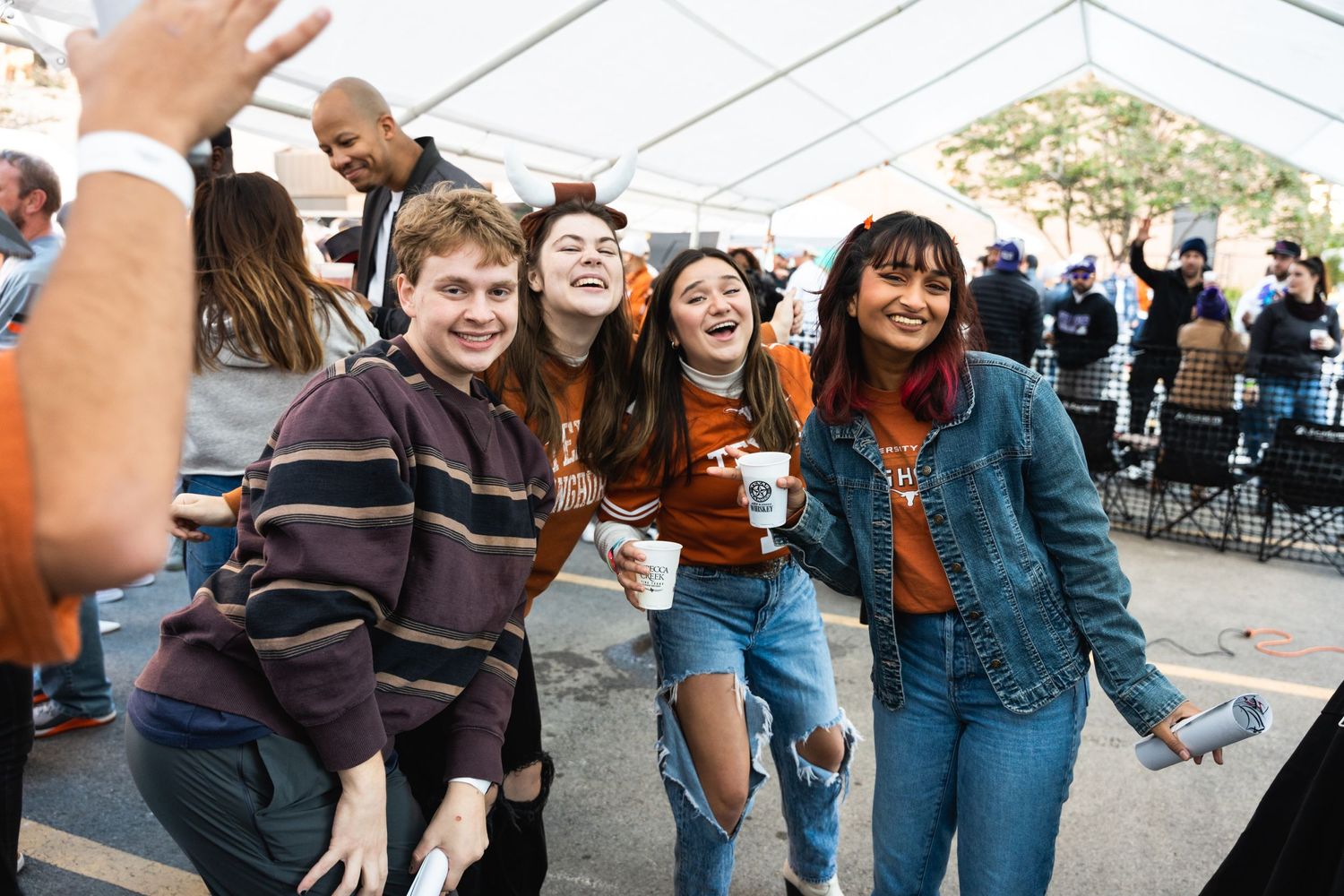Group of friends posing and laughing together at an outdoor university gathering.