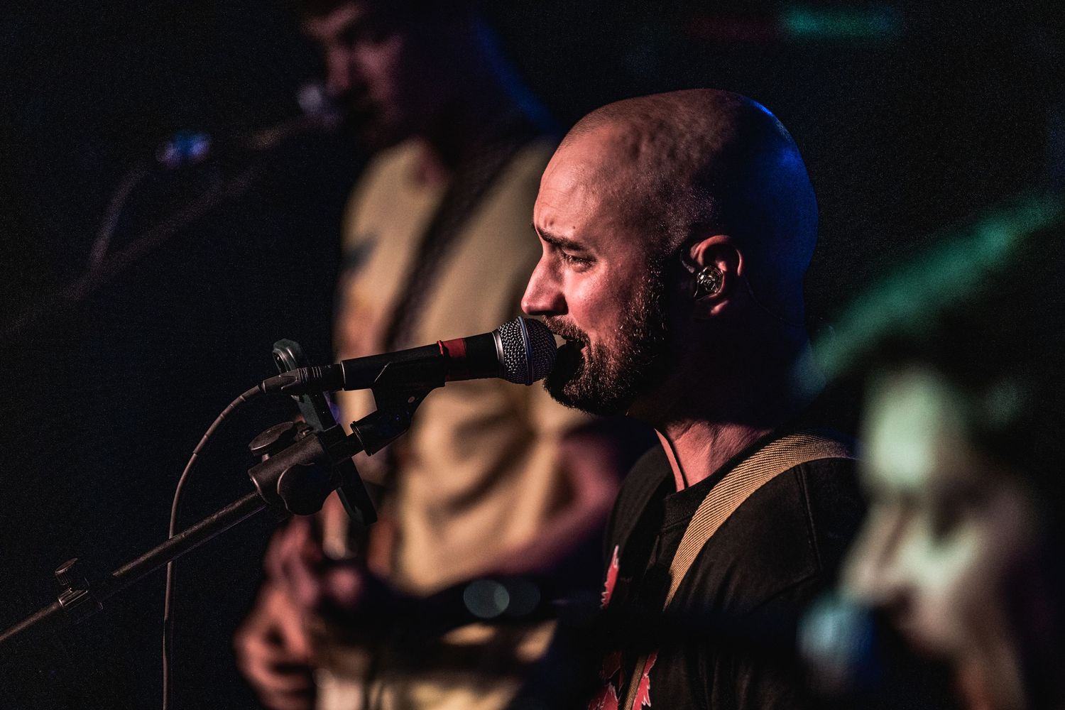 Close-up of musician singing into microphone with dramatic stage lighting.