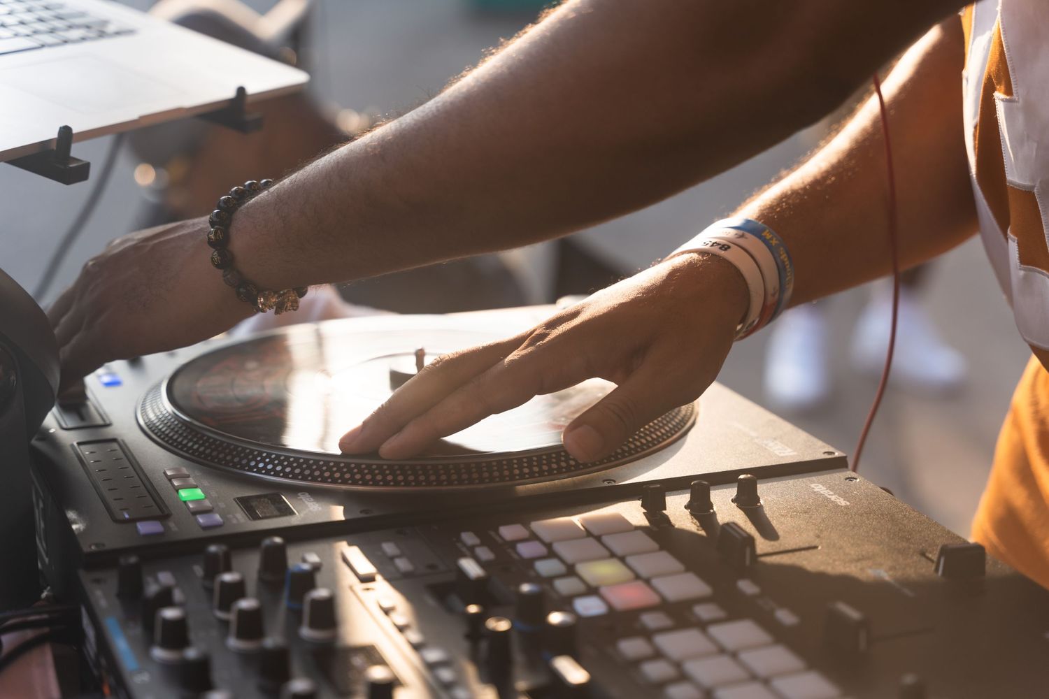DJ mixing on professional equipment with hands adjusting controls at an event.
