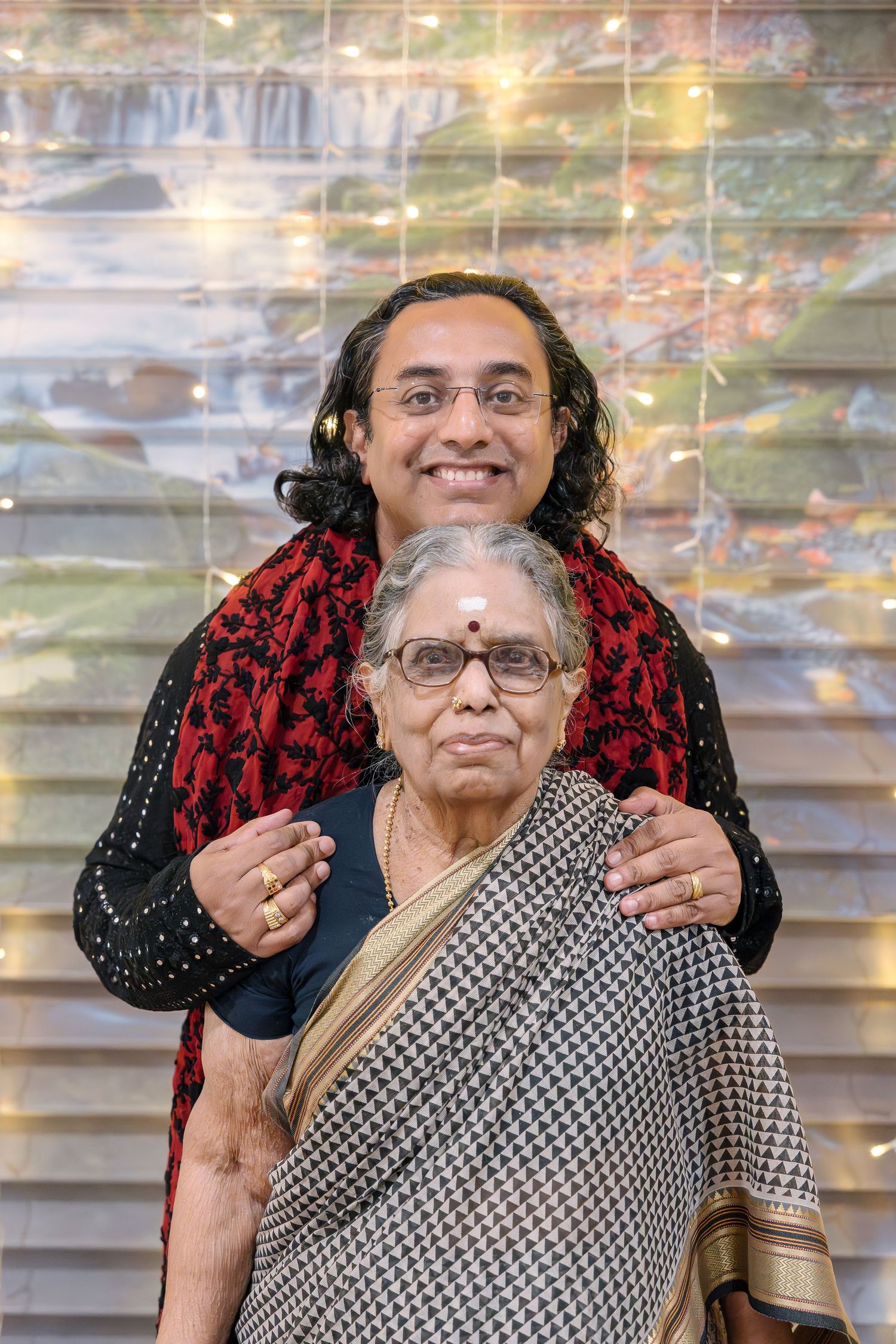 Two people in traditional Indian attire standing together against a sparkly backdrop.