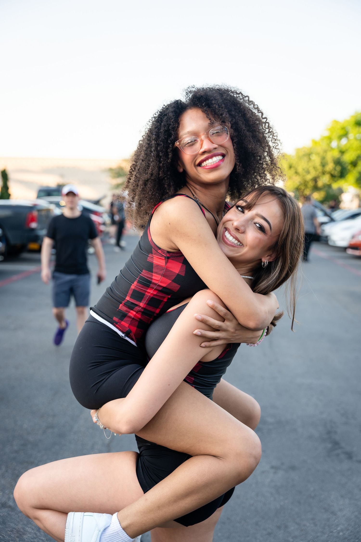 Friends sharing a joyful hug and laugh in a sunny outdoor setting.