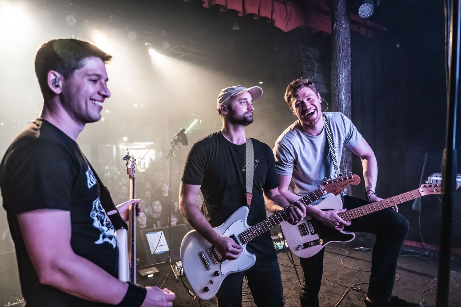 Musicians performing energetically on stage with guitars during a live concert performance.