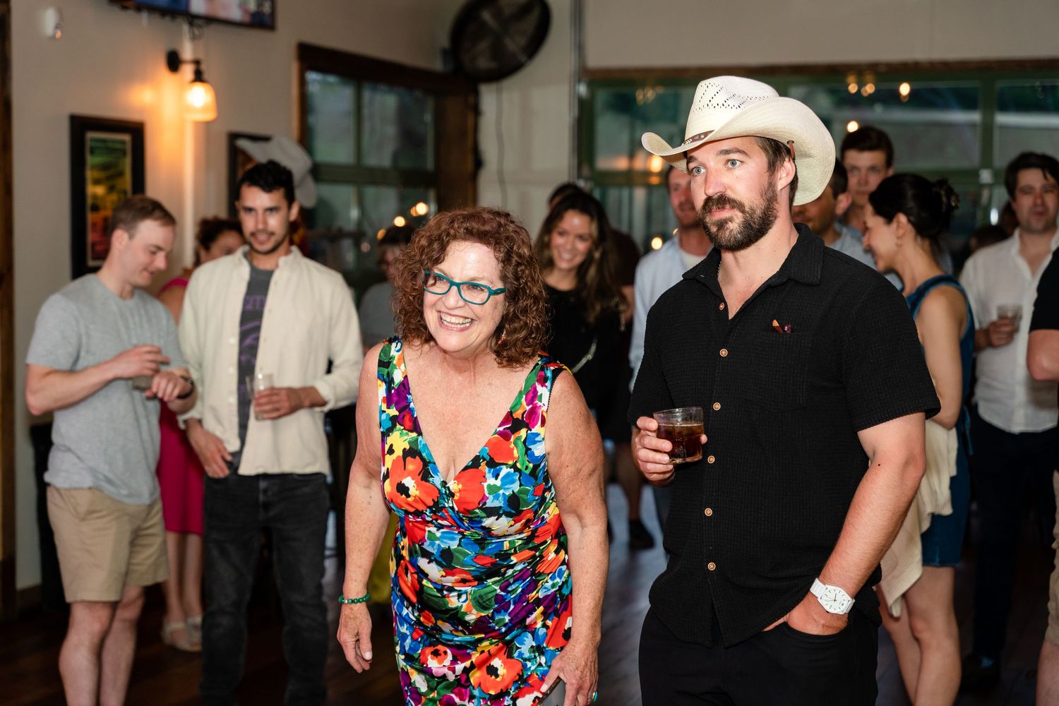 People enjoying themselves at an indoor social gathering with western-themed attire.