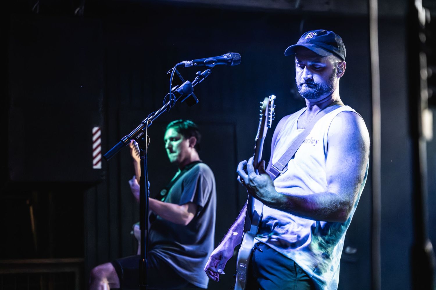 Musicians perform under blue stage lights during an intimate venue concert.