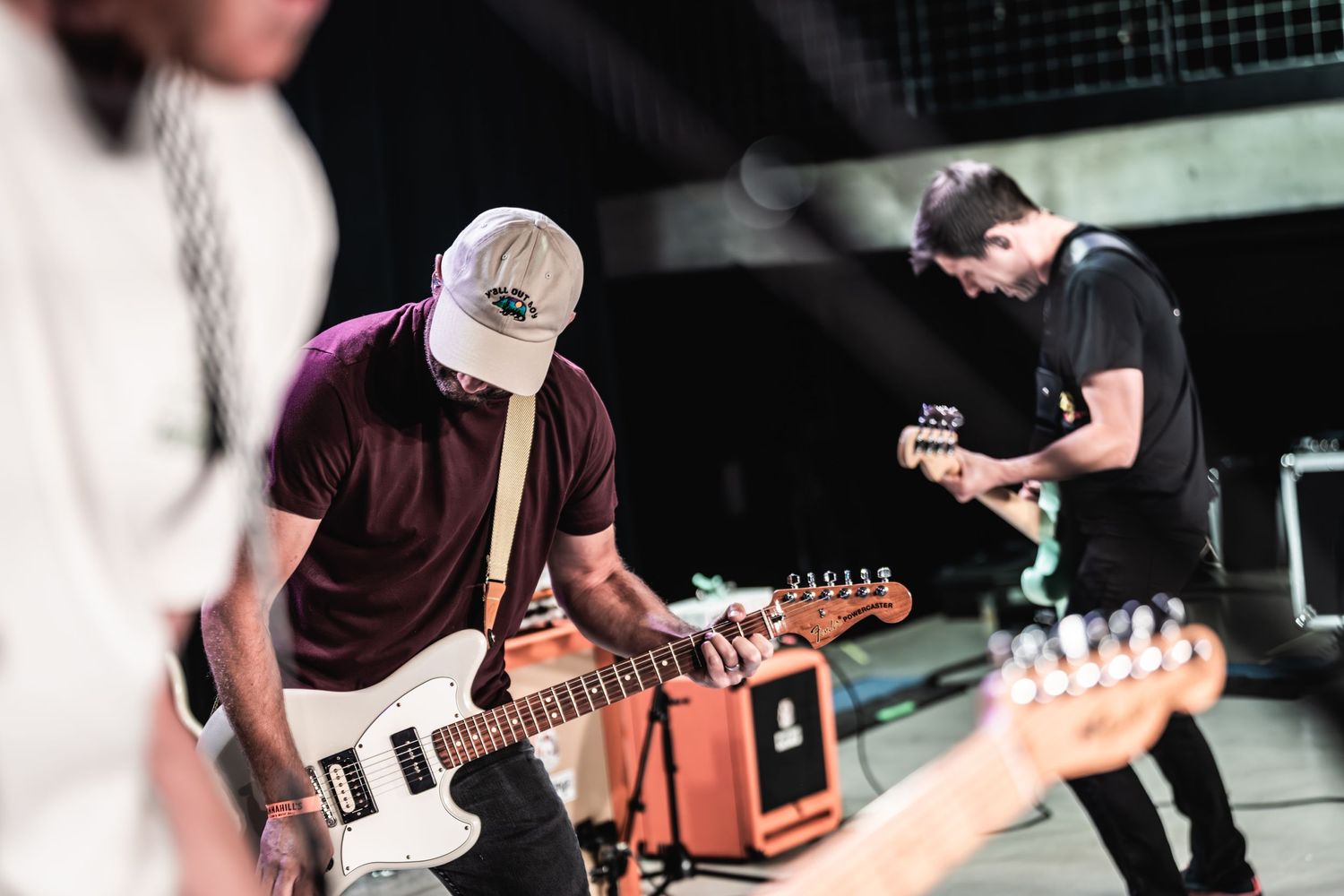 Musicians perform energetically on stage with electric guitars during a live concert performance.