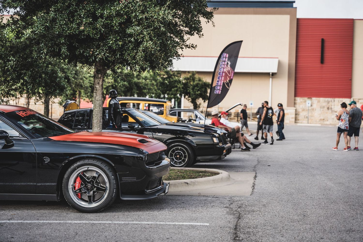 Car show gathering with modified vehicles lined up in a parking lot.