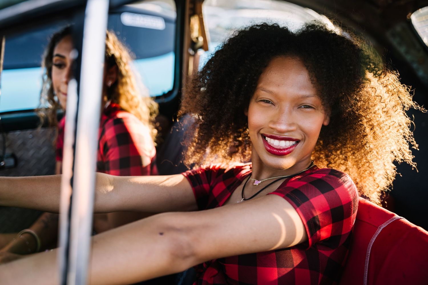Candid shot through car window showing joyful expression and natural hair.
