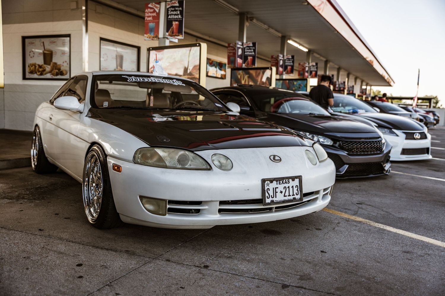 Classic white Lexus SC300 with aftermarket wheels displayed at car show.