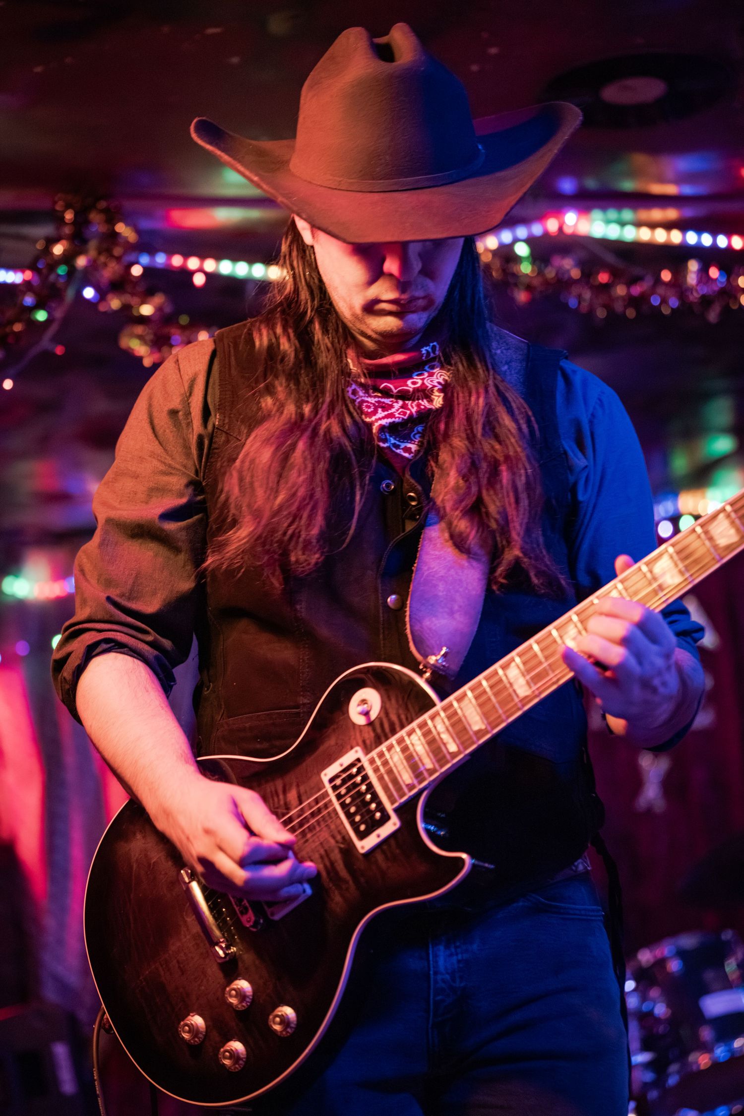 Guitar player performs on stage under colorful lighting at a nightclub venue.