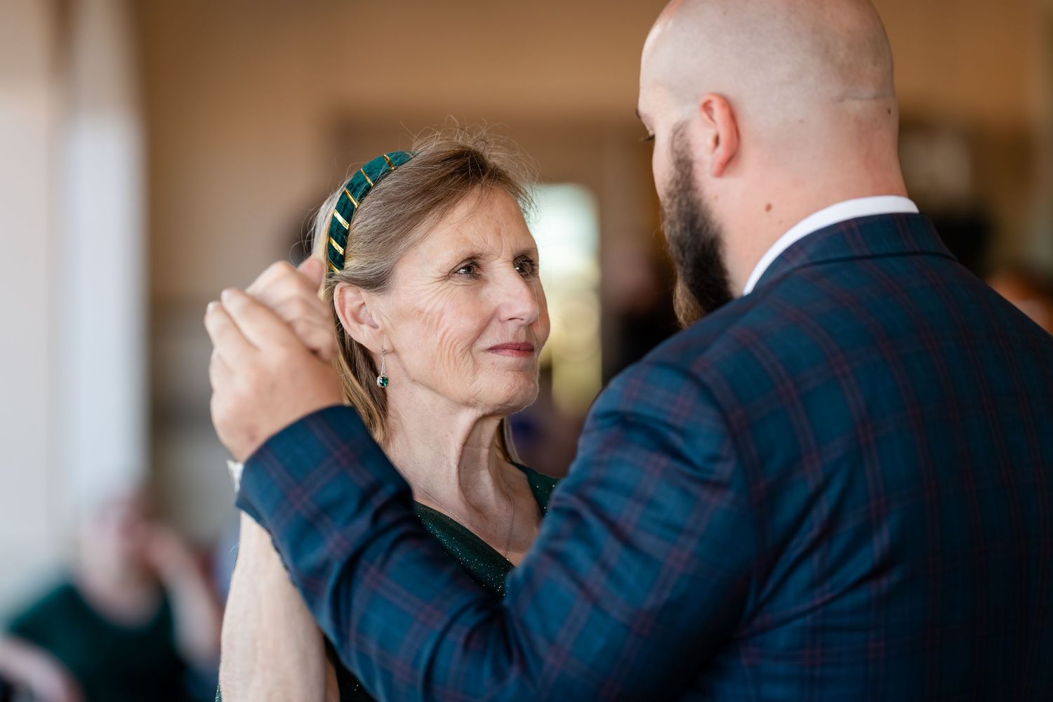 A couple shares a tender moment during their wedding celebration in a warm-lit indoor setting.