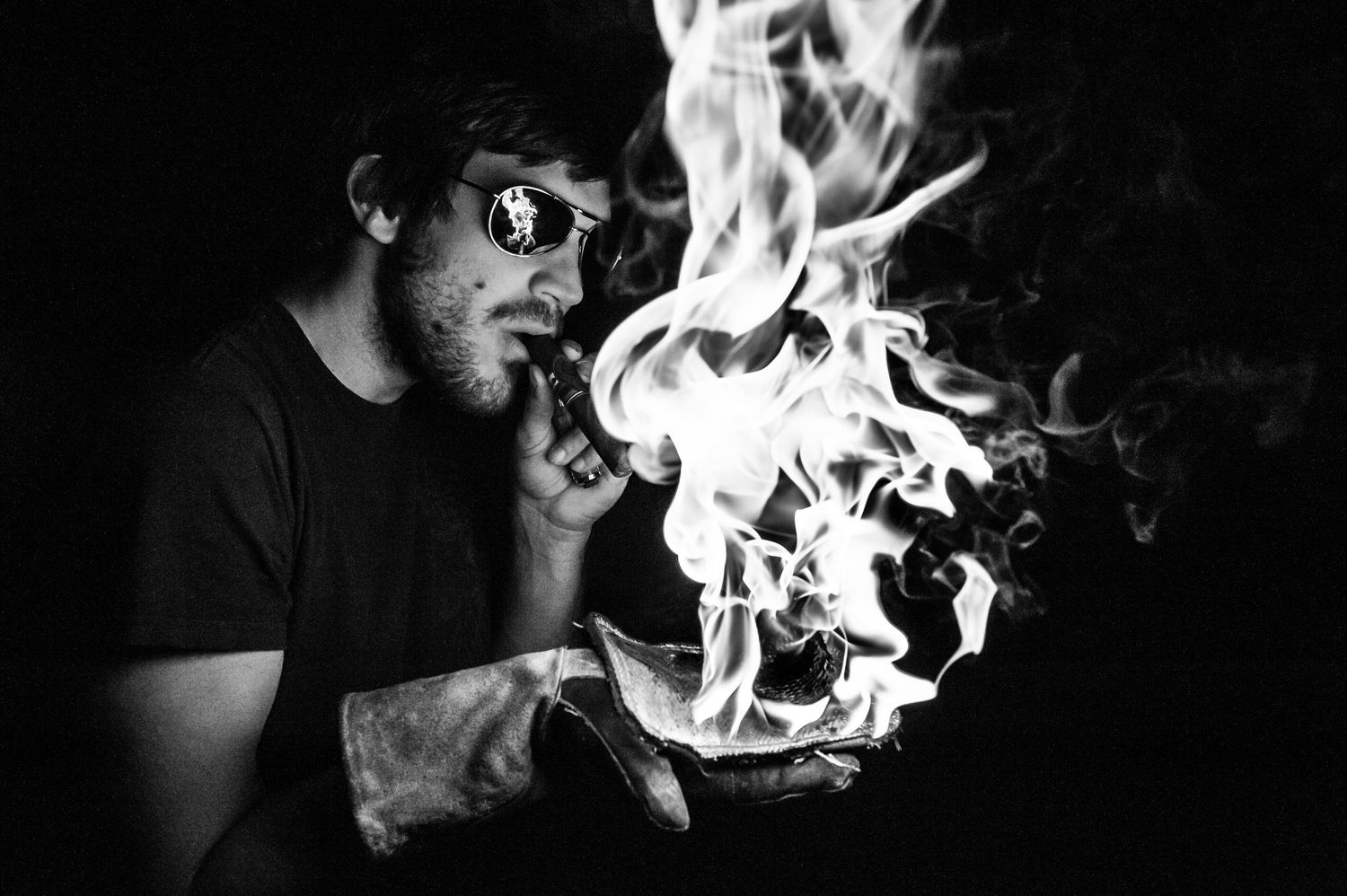 Dramatic black and white portrait of smoke billowing from someone exhaling in darkness.