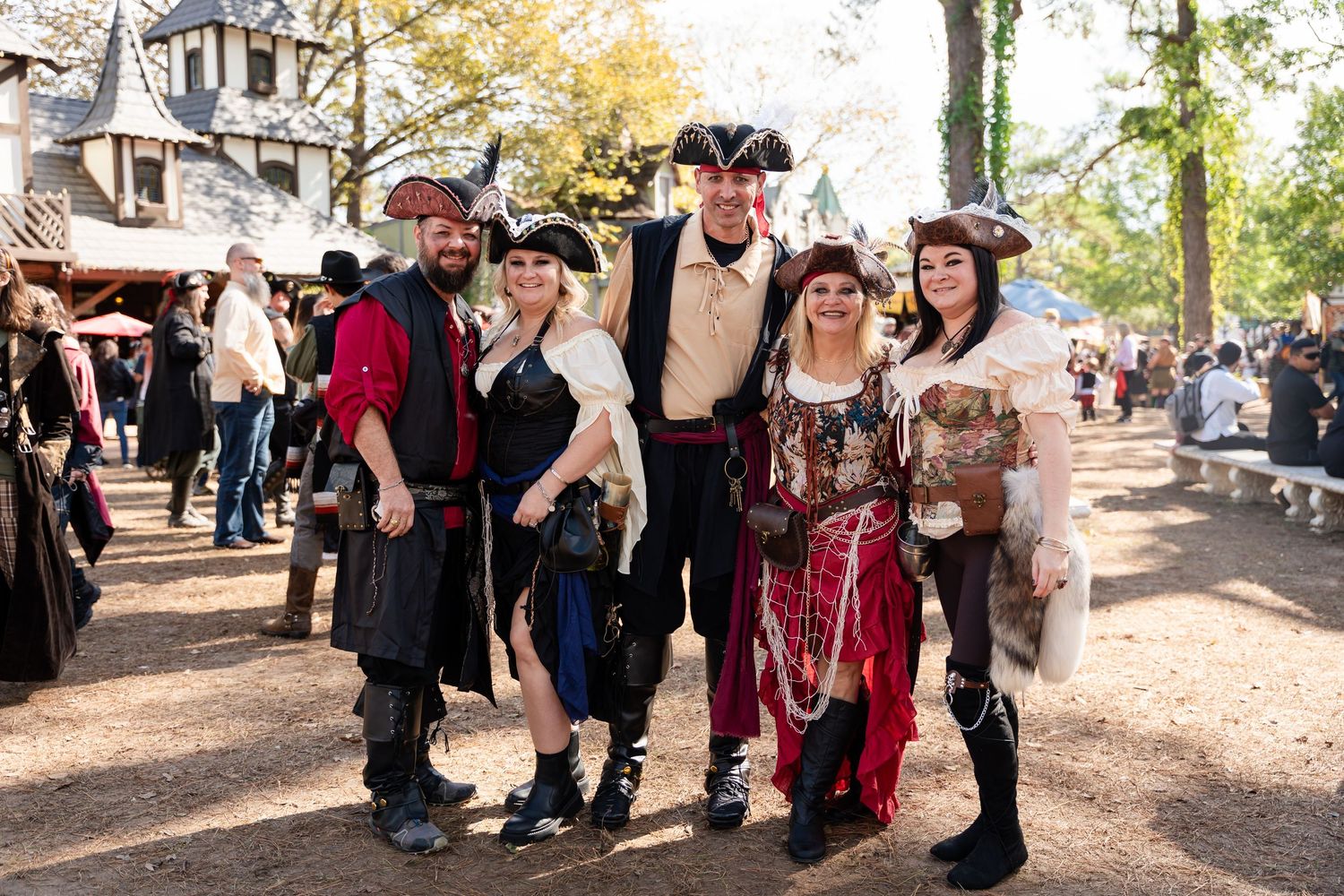A group of people in medieval and renaissance costumes gather outdoors during a festival event.