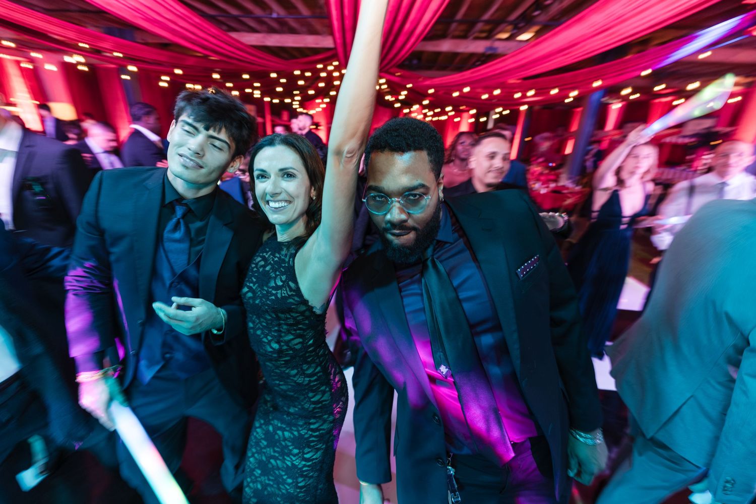 People dancing and enjoying themselves at a nightclub with vibrant pink and blue lighting effects.