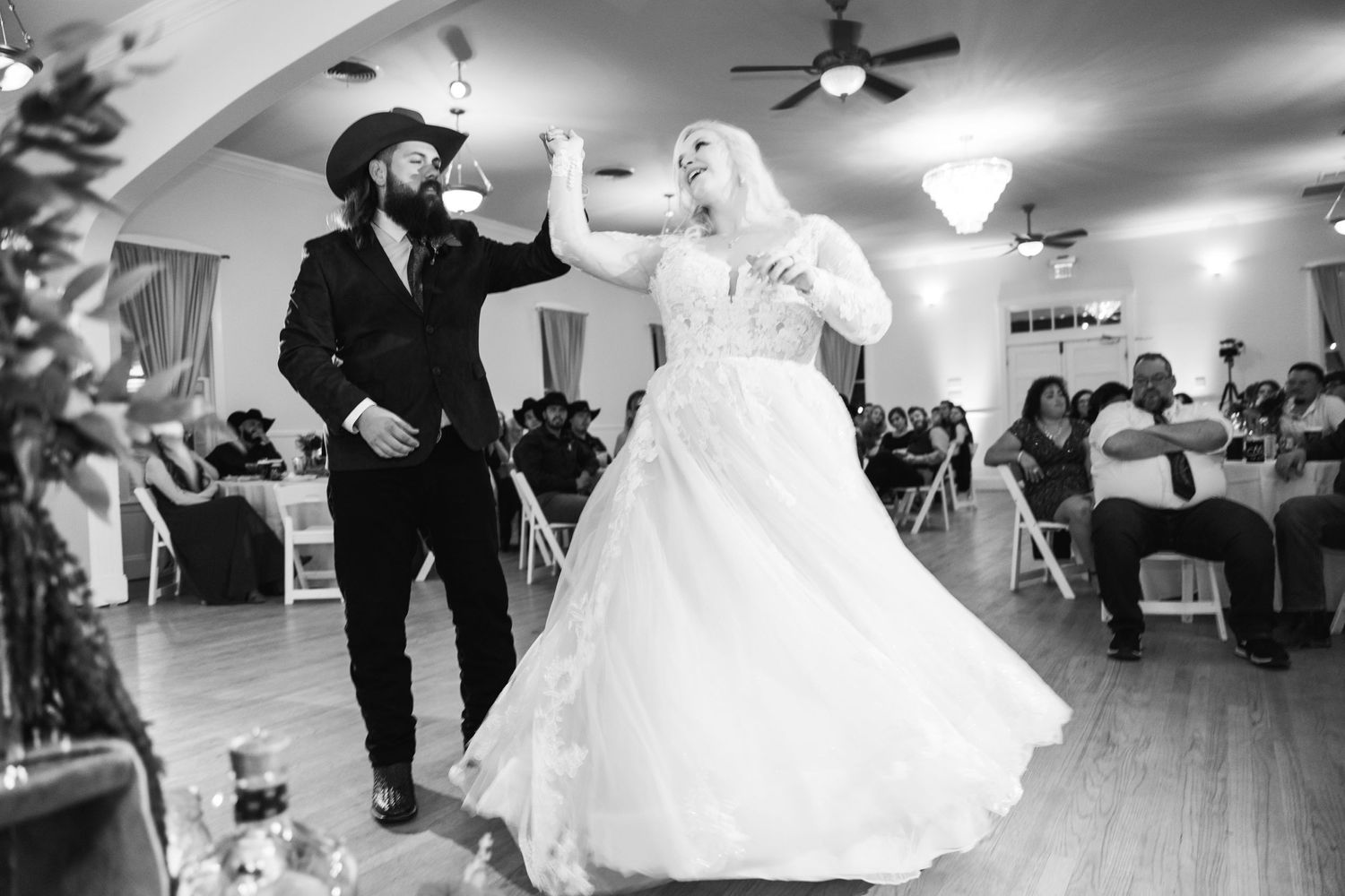 Black and white photo of a couple dancing energetically at their wedding reception.
