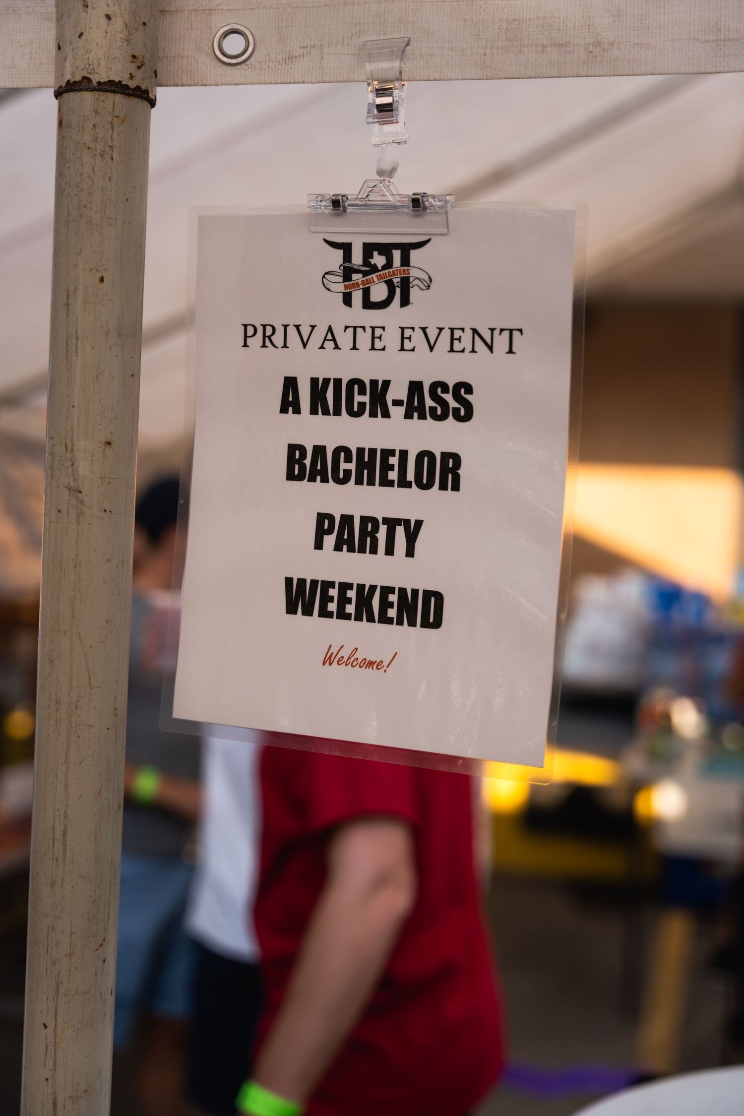 A sign for a private bachelor party weekend event hangs from a pole.