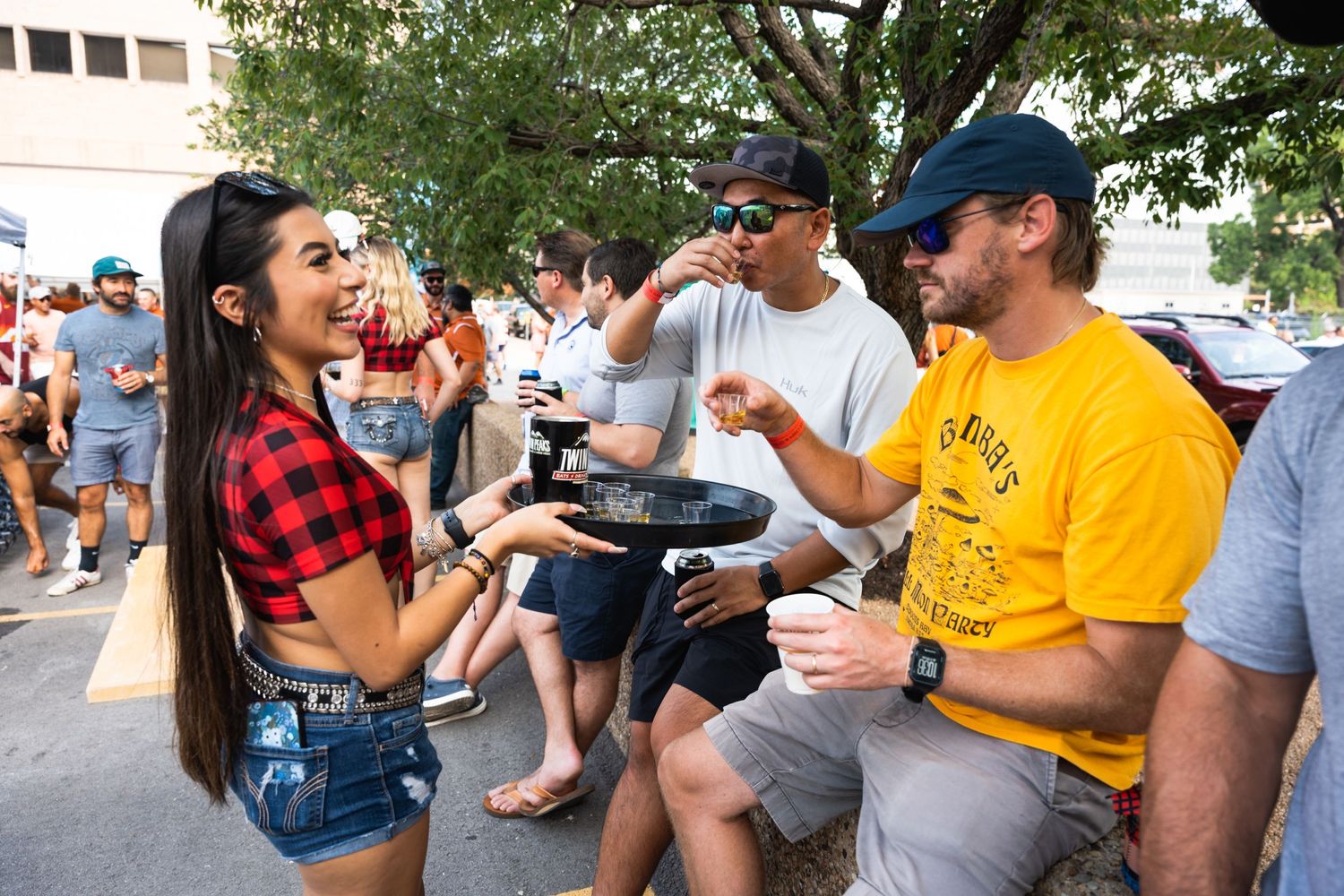 Fans socializing and gesturing at an outdoor tailgate party.