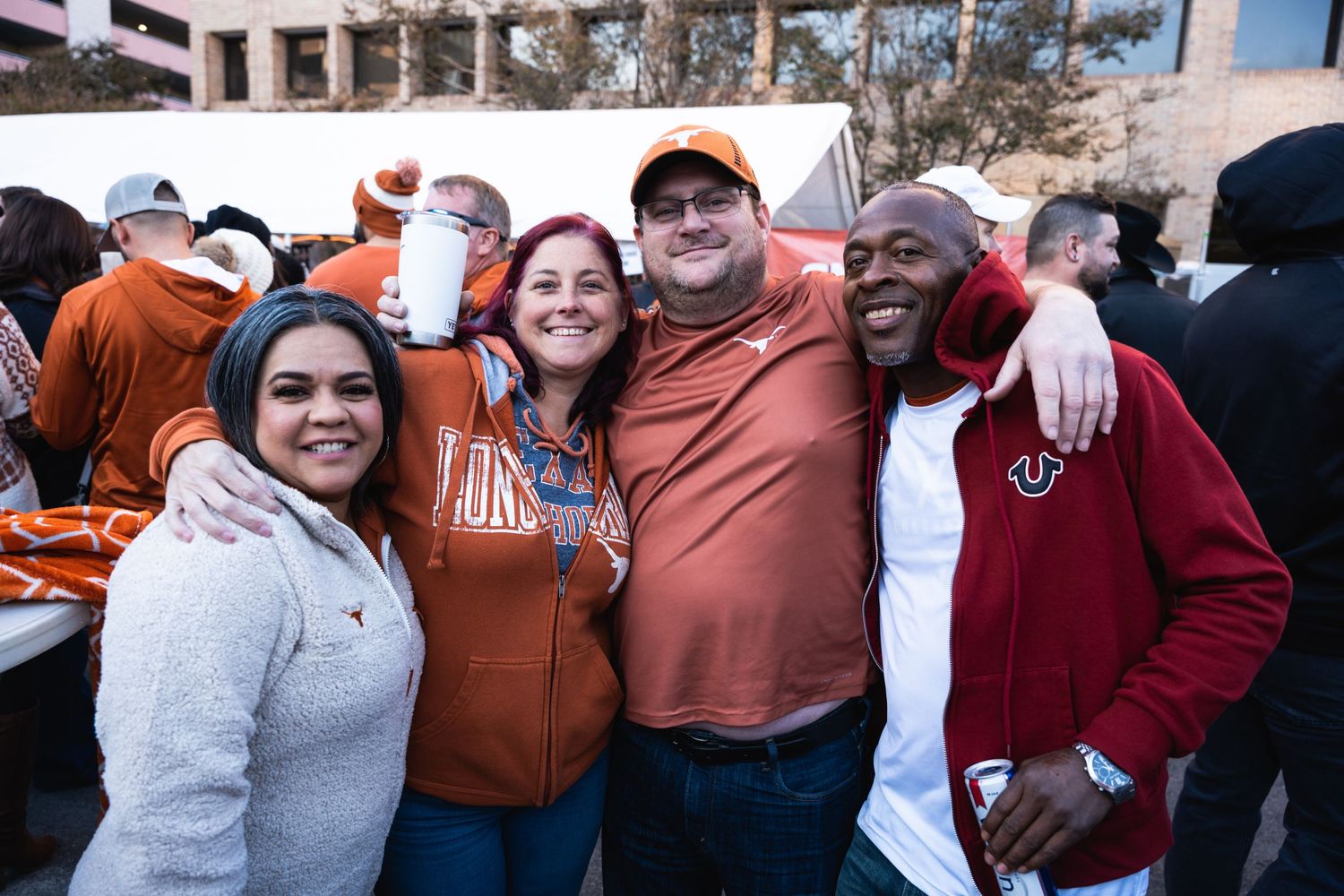 Diverse group of sports fans posing together at an outdoor tailgate event.
