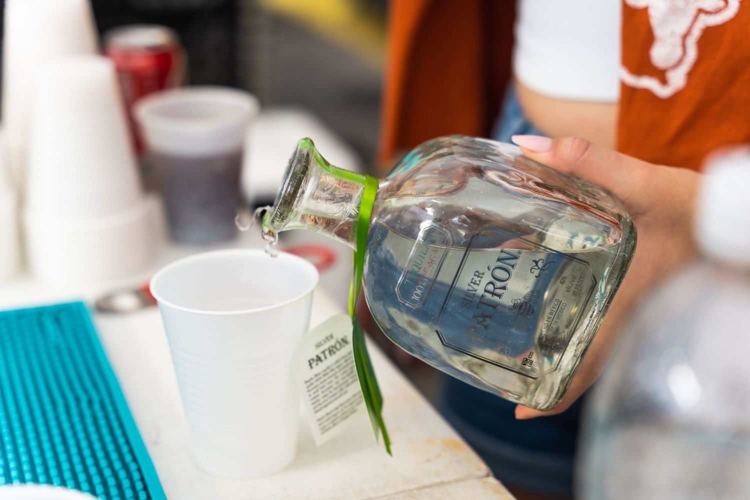 Close-up shot of a clear liquor bottle being poured into cups.