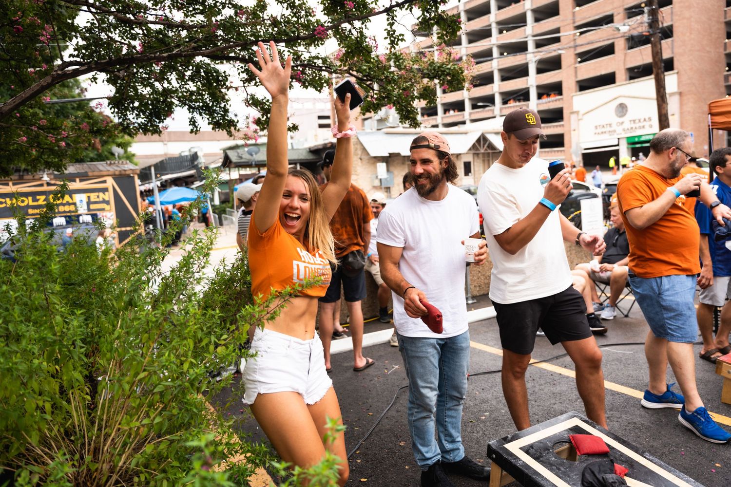 Crowd celebrates during outdoor tailgate party with games.