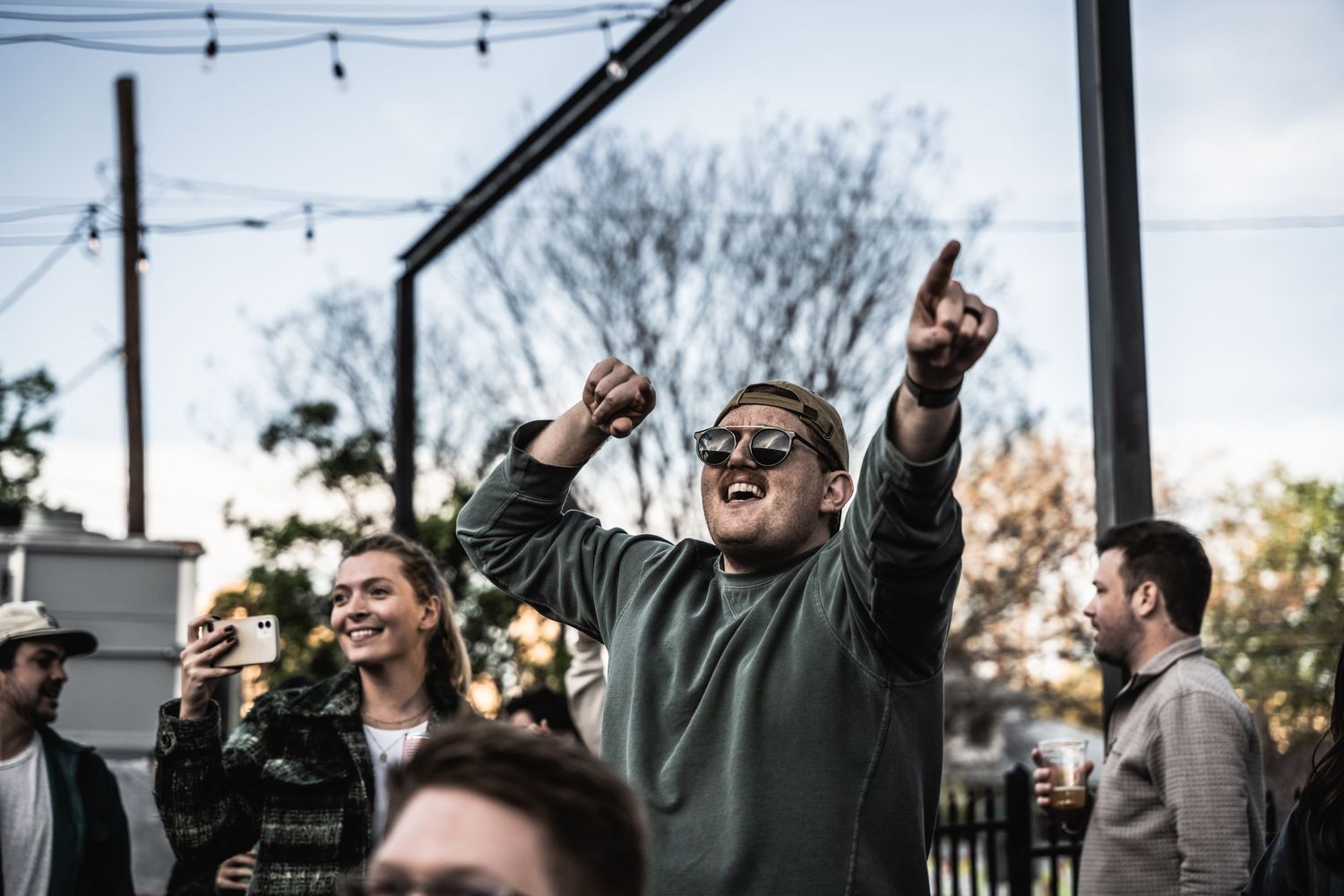 Concert attendees cheering and raising hands during outdoor performance.