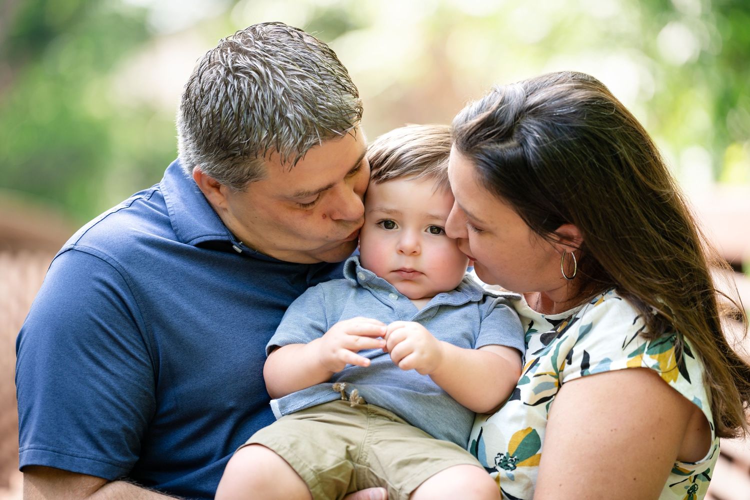 An intimate family moment captured outdoors with gentle embraces and natural lighting.