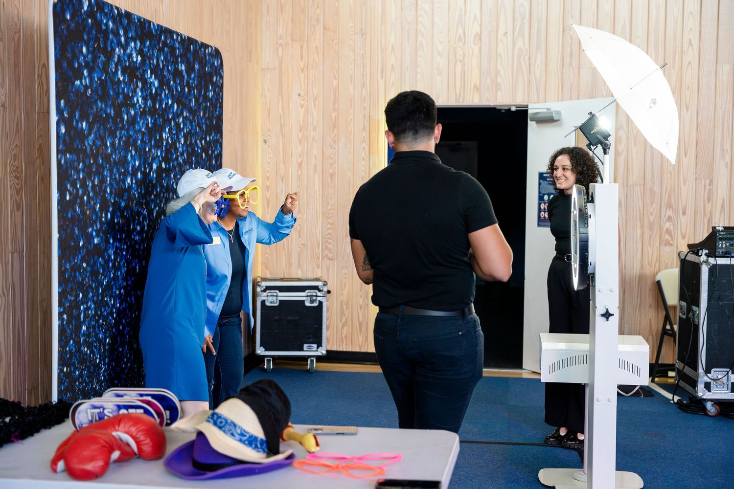 Behind the scenes photo shoot setup with lighting equipment, props, and a photography backdrop in a studio space.