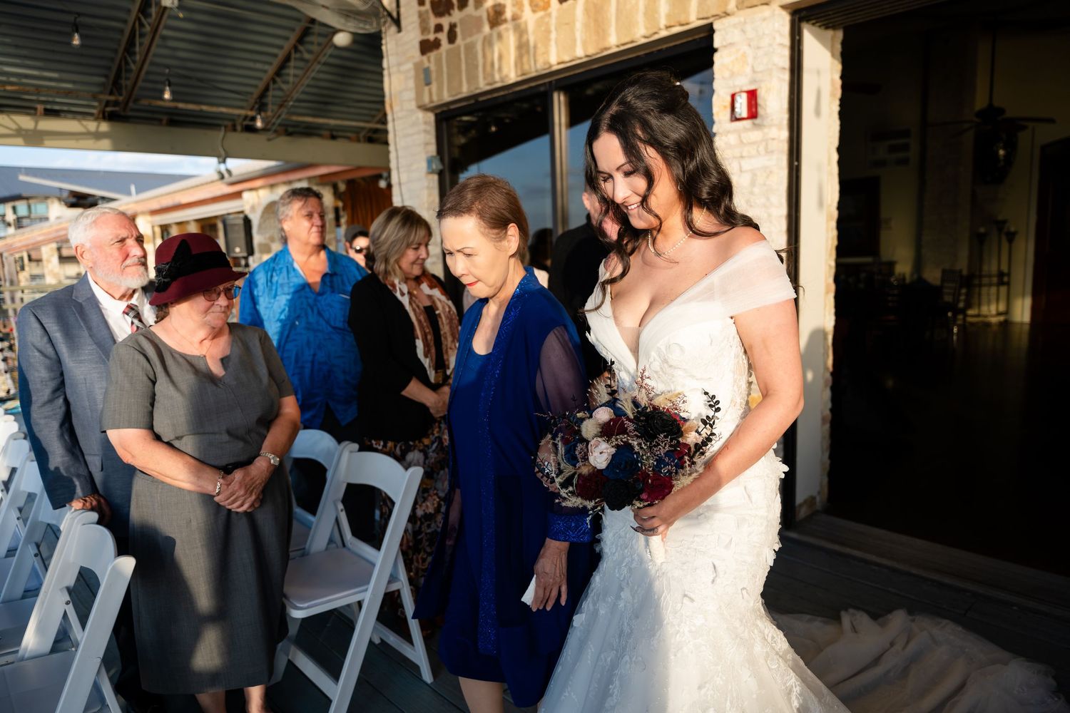 Wedding party members greeting guests before ceremony in outdoor venue.