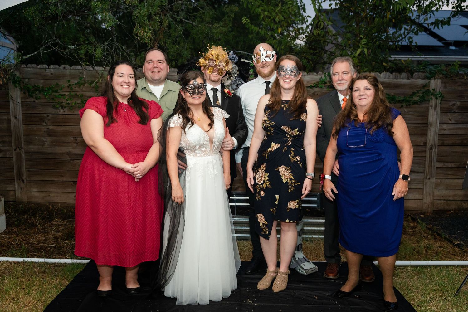 Wedding party poses for group photo with couple in evening attire.