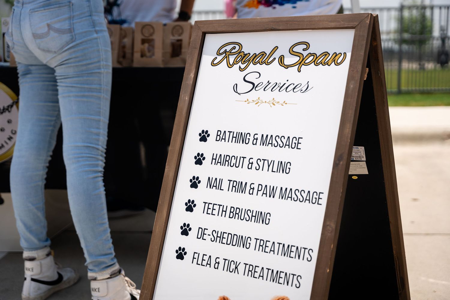A wooden sign board displays Royal Space Services offering various pet grooming and massage treatments.