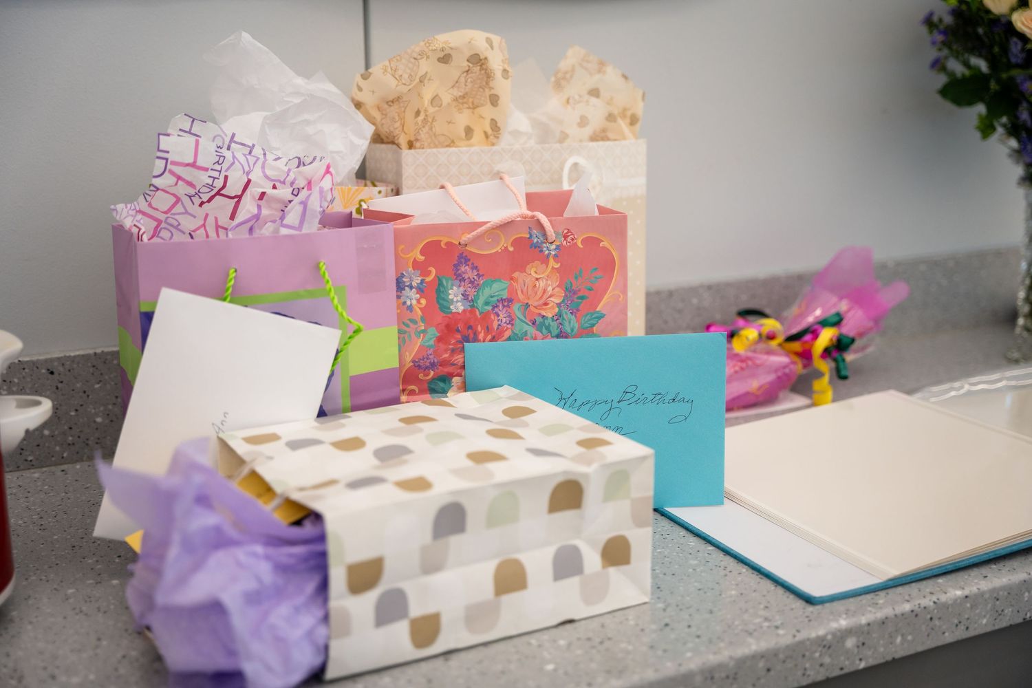 Colorful birthday gift boxes and cards arranged on gray counter.