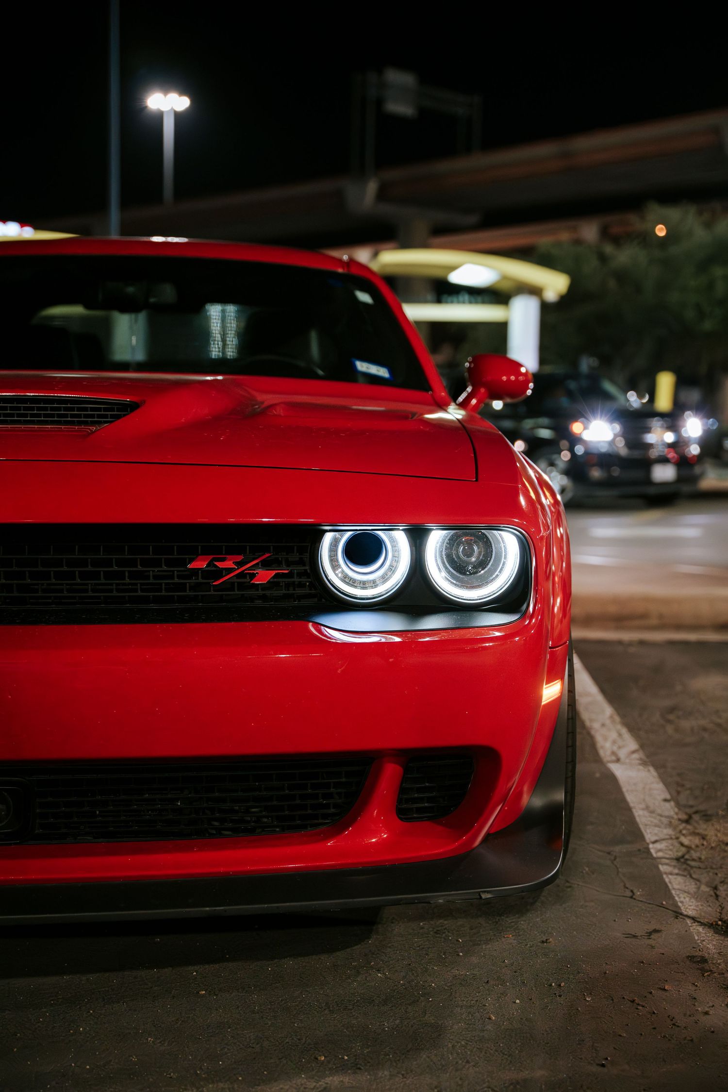 Close up of red Dodge Challenger headlight and grille at night.