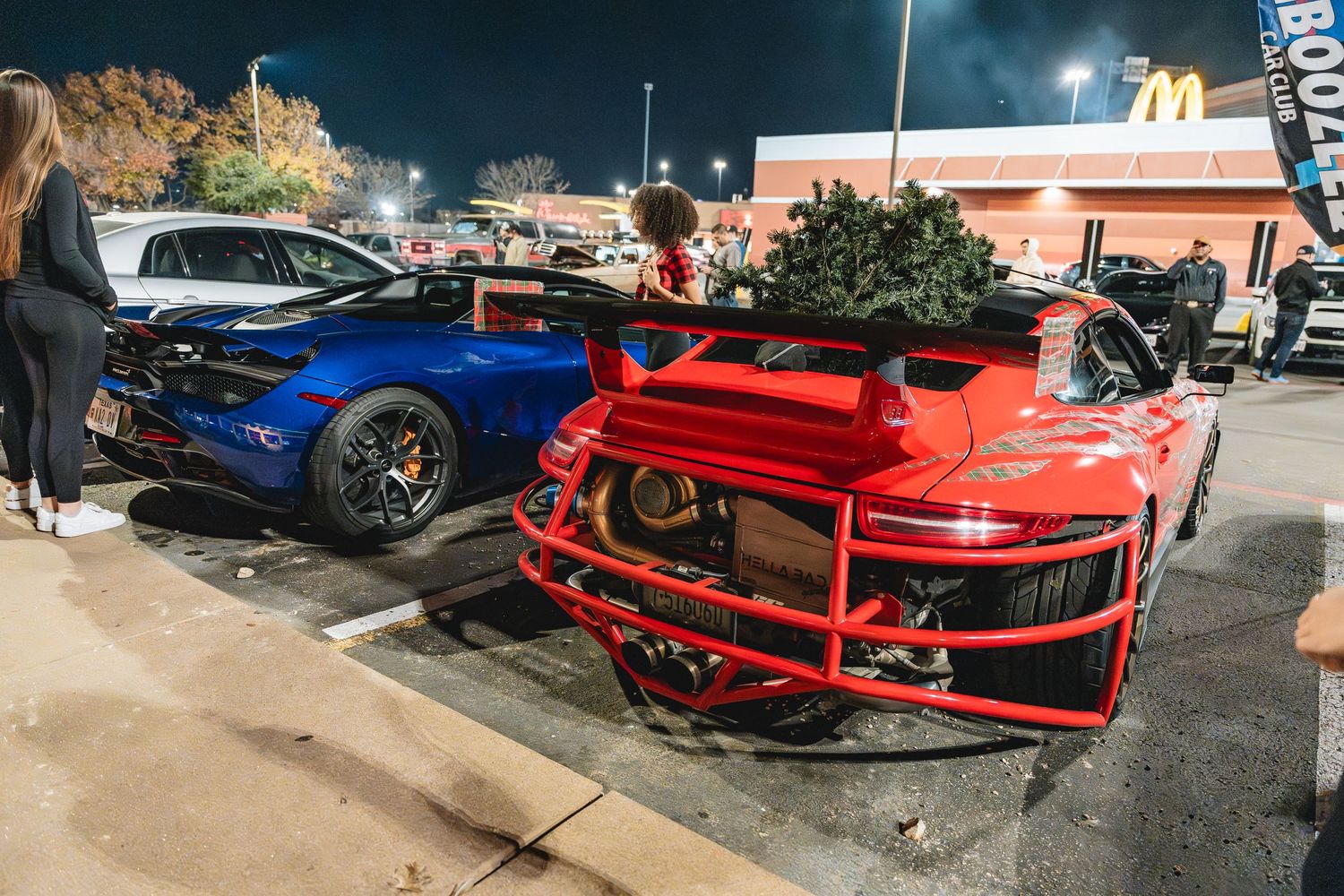 Blue and red sports cars parked side by side at a nighttime gathering.