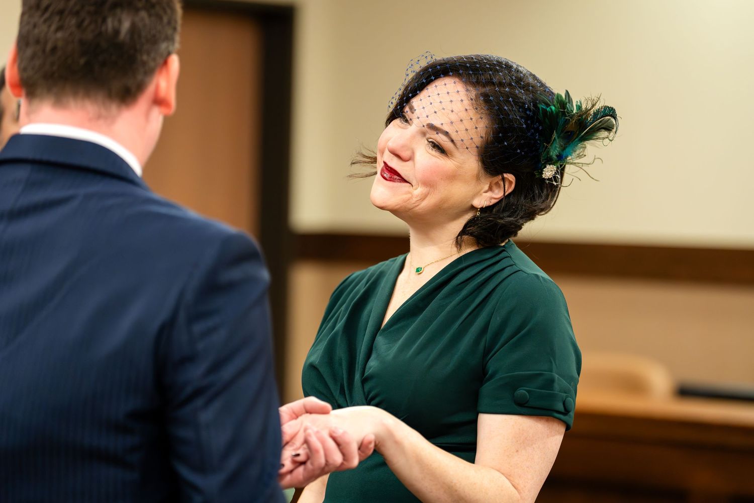 A couple shares a touching moment while exchanging vows in a courthouse.
