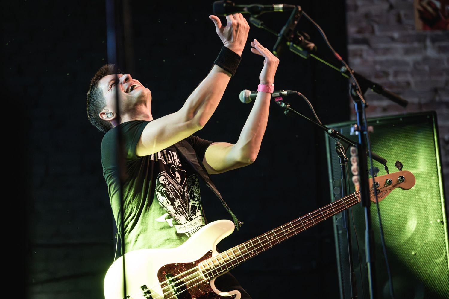 Bass player performs energetically on stage with dramatic lighting at a rock concert.