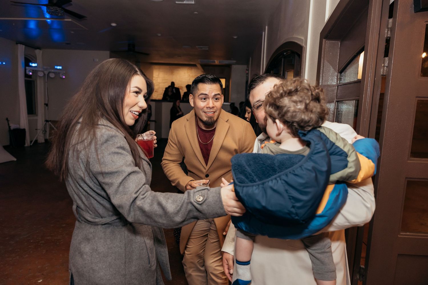 Group interacts with young child at an indoor event.