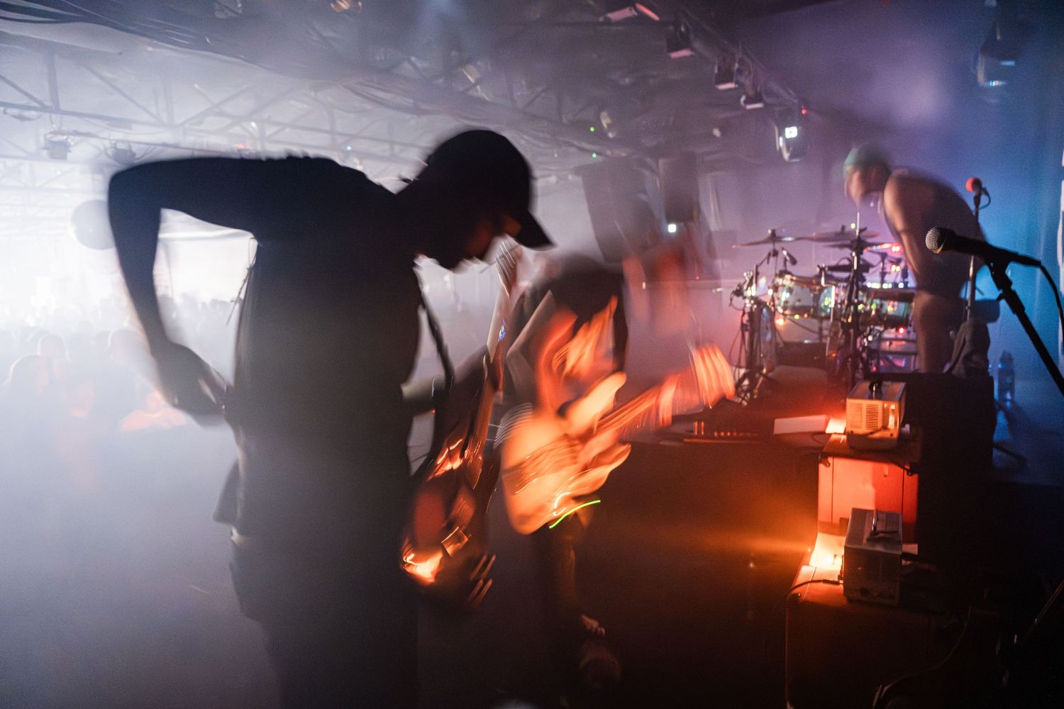 A silhouetted performer plays guitar on a smoke-filled stage with dramatic lighting effects.