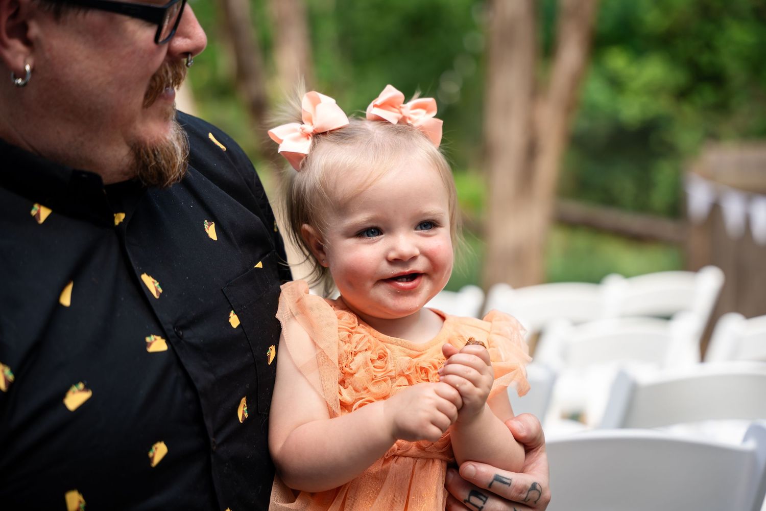 A joyful toddler in an orange dress at an outdoor event.