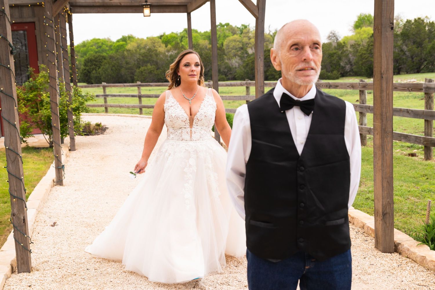 A wedding party member and bride walking under a rustic wooden pergola.