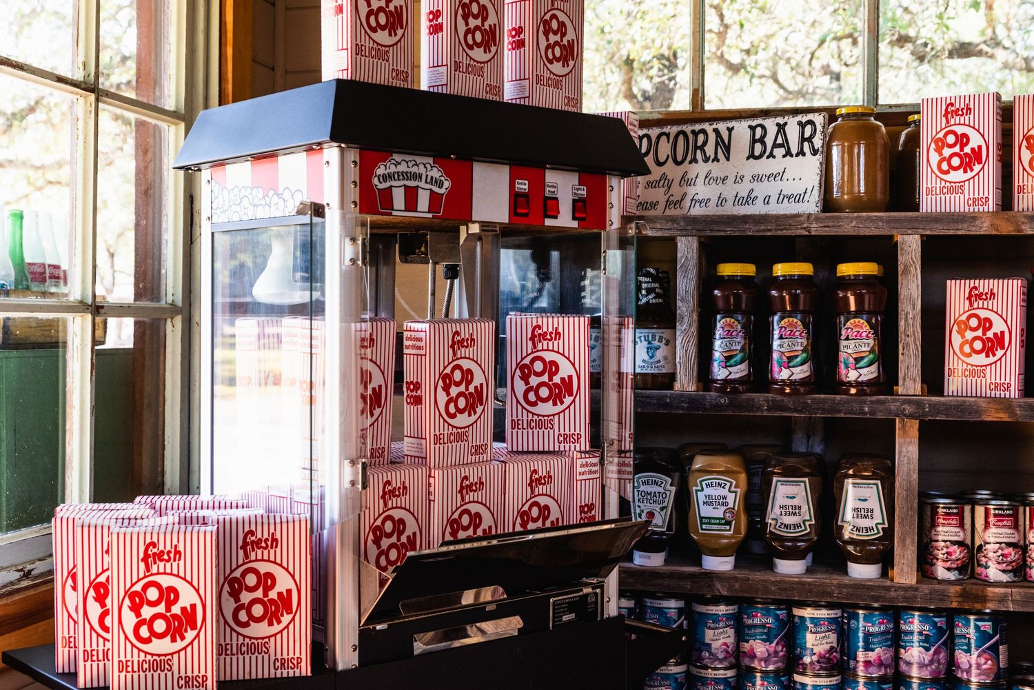 Retro popcorn machine station with stacks of classic striped boxes at wedding reception.