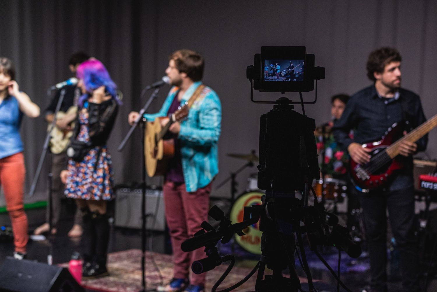 Band performs on stage with video equipment visible in foreground.