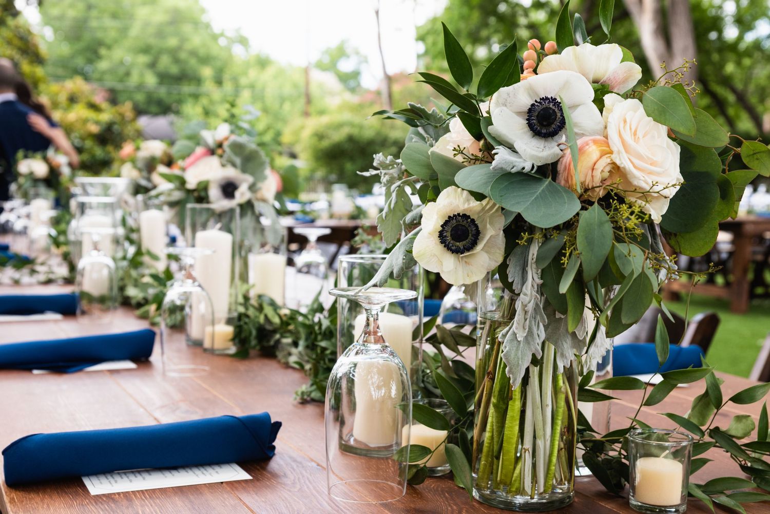 Wedding centerpiece with white anemone flowers and eucalyptus on navy blue table setting.