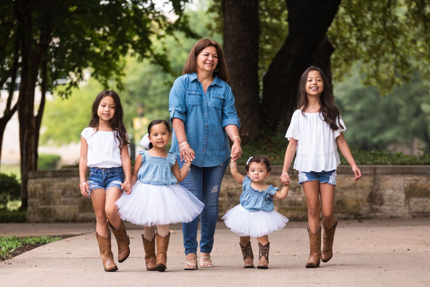 A family walks together on a path wearing coordinated blue and white outfits with cowboy boots.