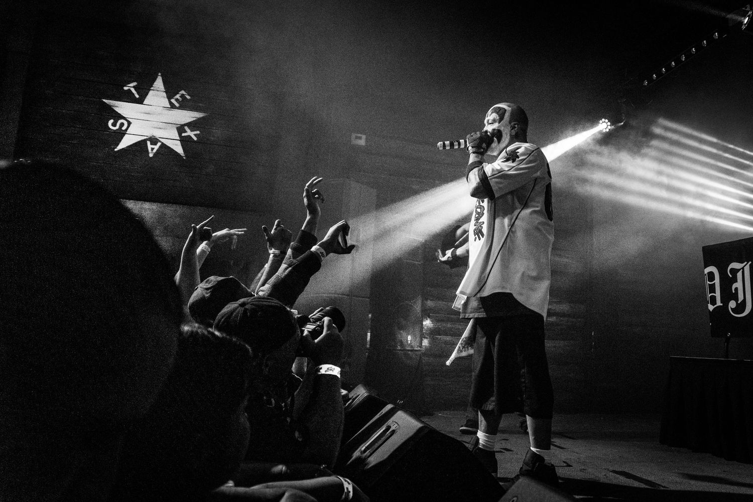 Concert performer on stage with dramatic backlight and crowd silhouettes beneath a star decoration.