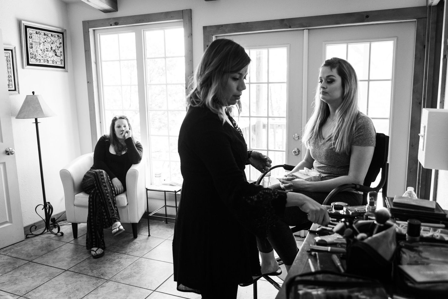 A black and white photograph showing wedding preparation activities indoors.