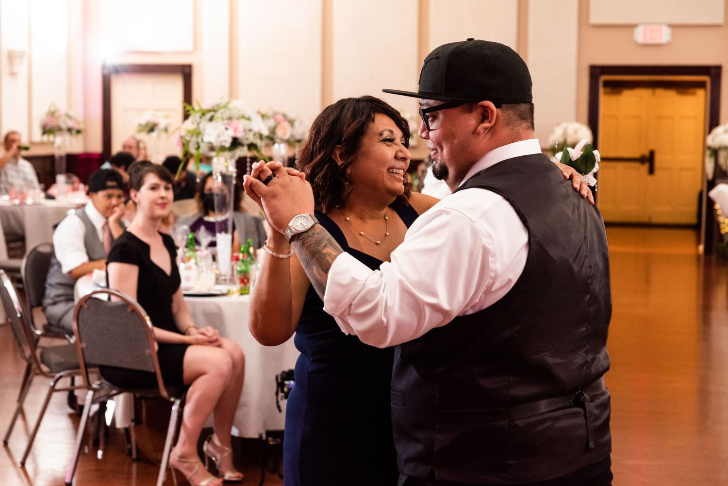 Couples dancing together at an indoor reception with elegant decor and mood lighting.