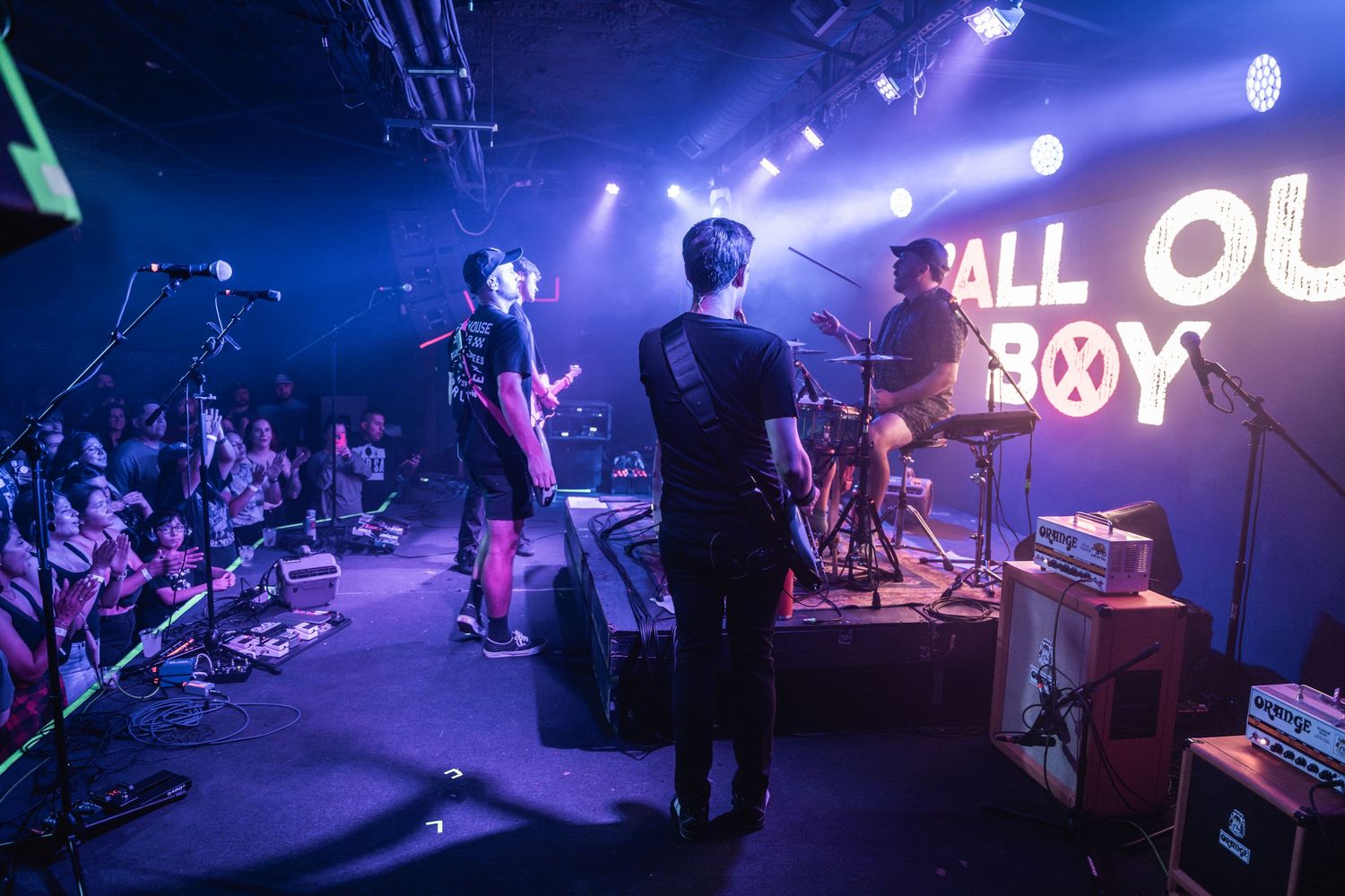 Concert stage illuminated with purple lights and performers creating an energetic atmosphere during a live show.